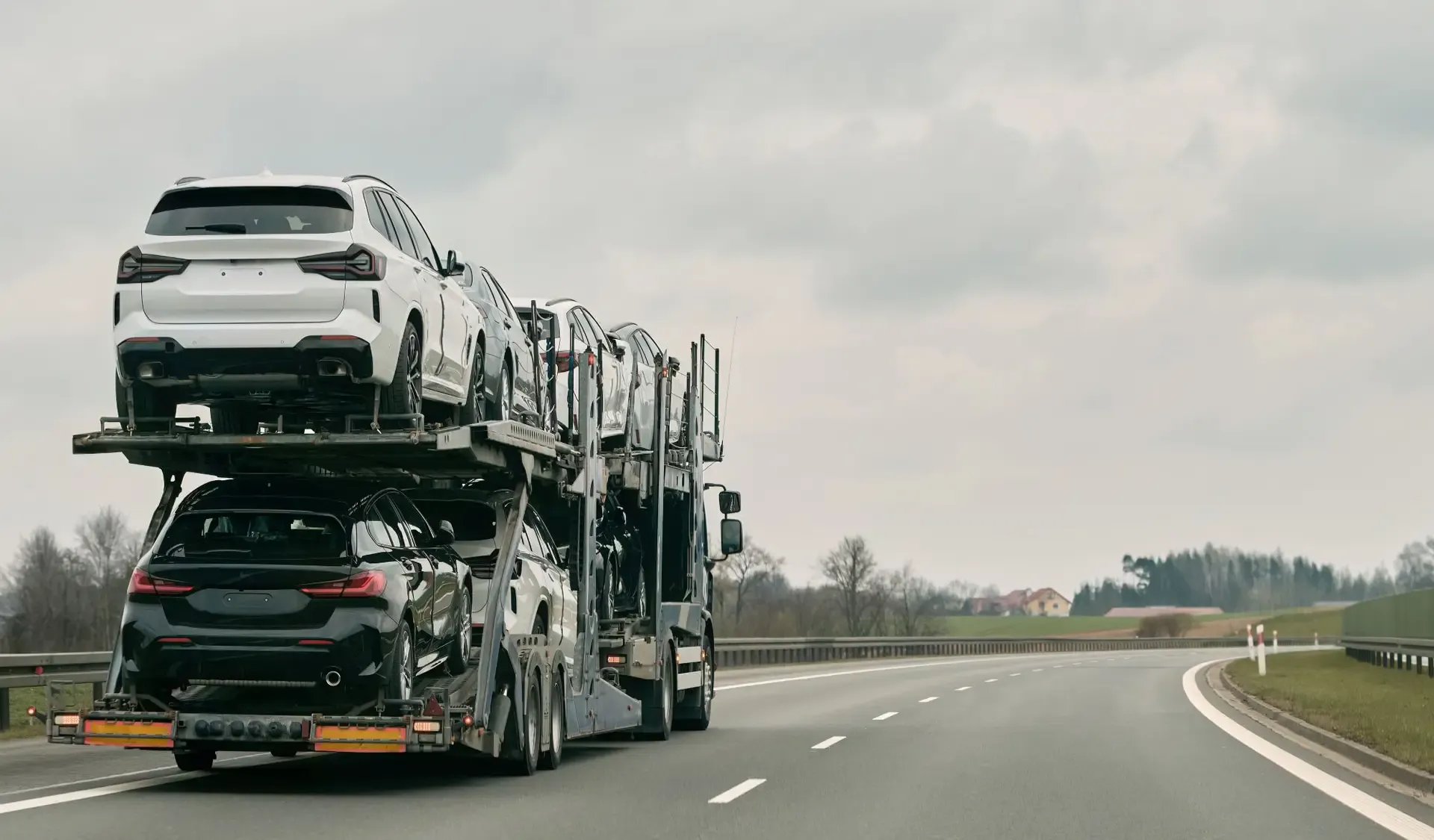 Car transporter loaded with new cars under a grey Nordic sky