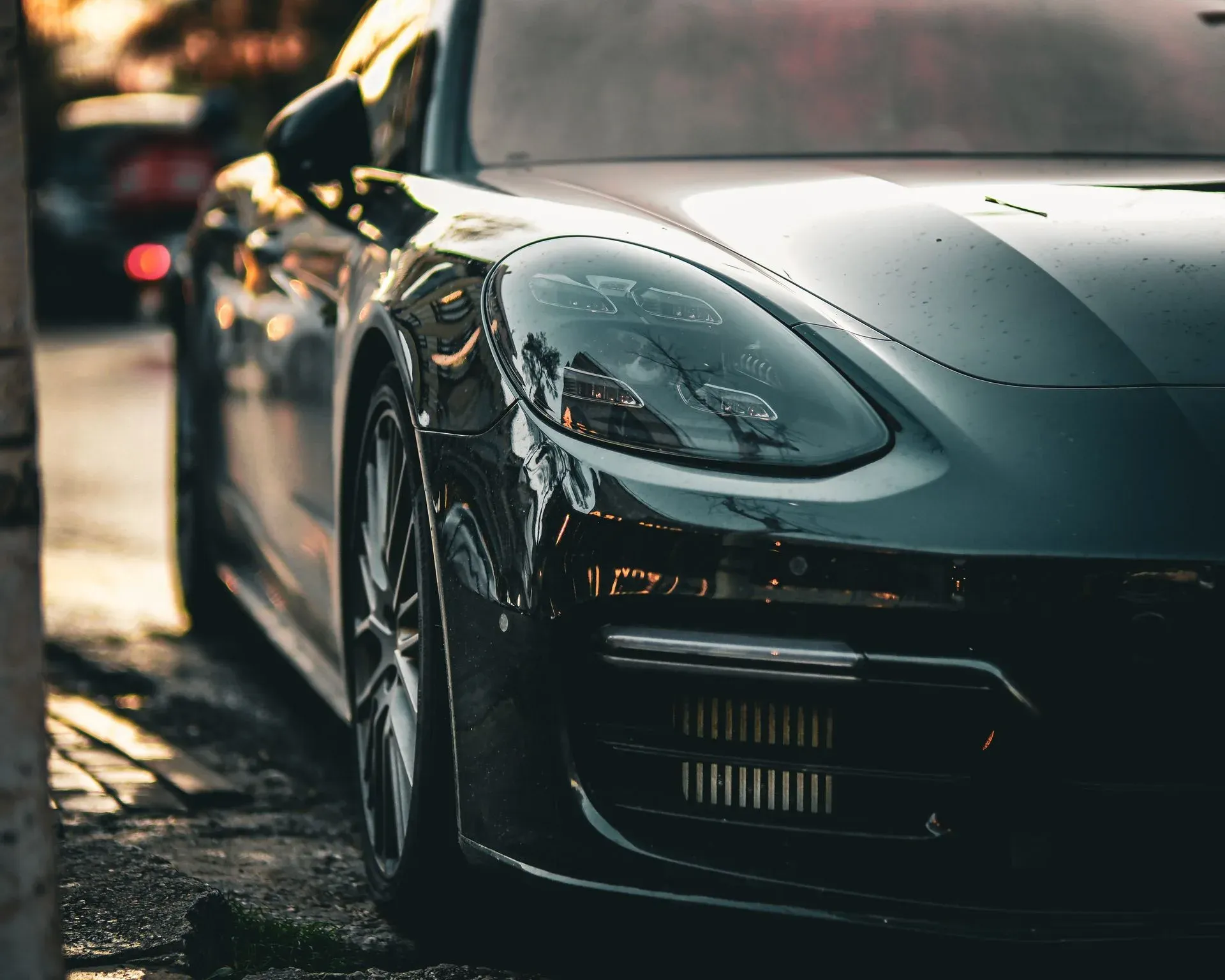 Front of a dark grey Porsche Panamera parked on a city street